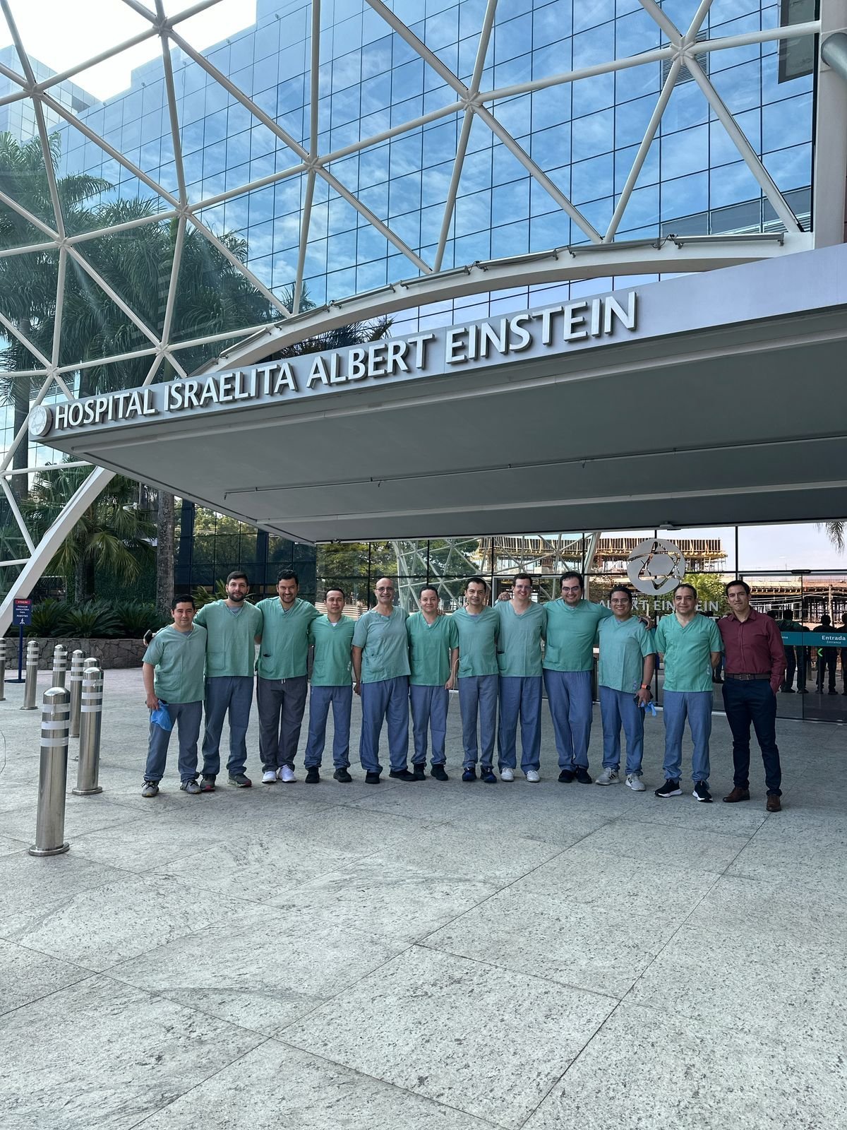 Group of people in teal shirts standing in a line outside Hospital Graelita Albert Einstein building