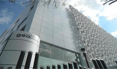 Modern glass and metal office building facade with gear signage, shot from below against blue sky