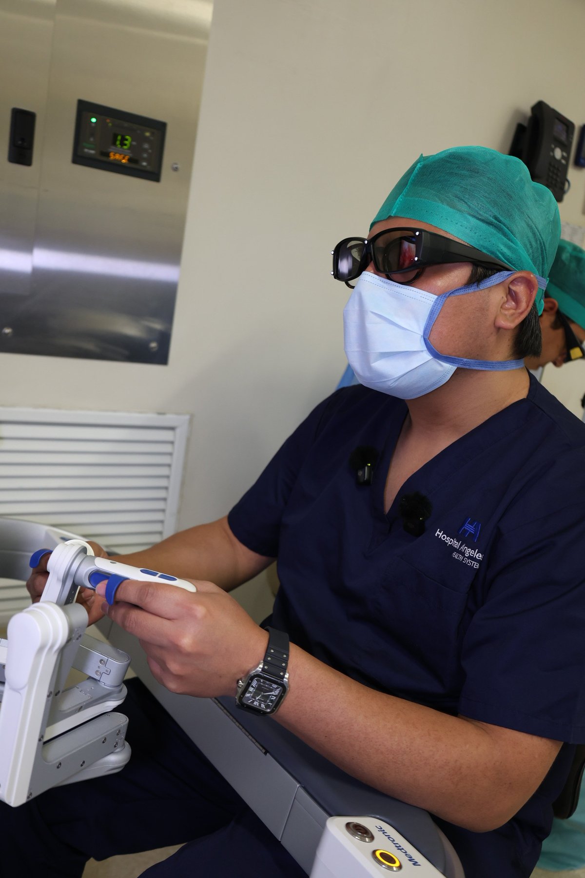 Healthcare professional in surgical cap and mask holding medical equipment in a clinical setting