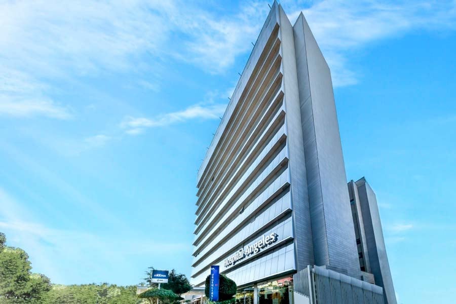 Modern tall residential or commercial building with distinctive angular architecture and horizontal window lines against blue sky