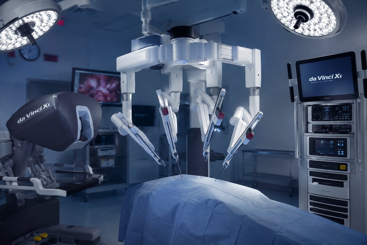Modern surgical operating room with robotic surgical system, overhead LED lights, monitors, and control equipment
