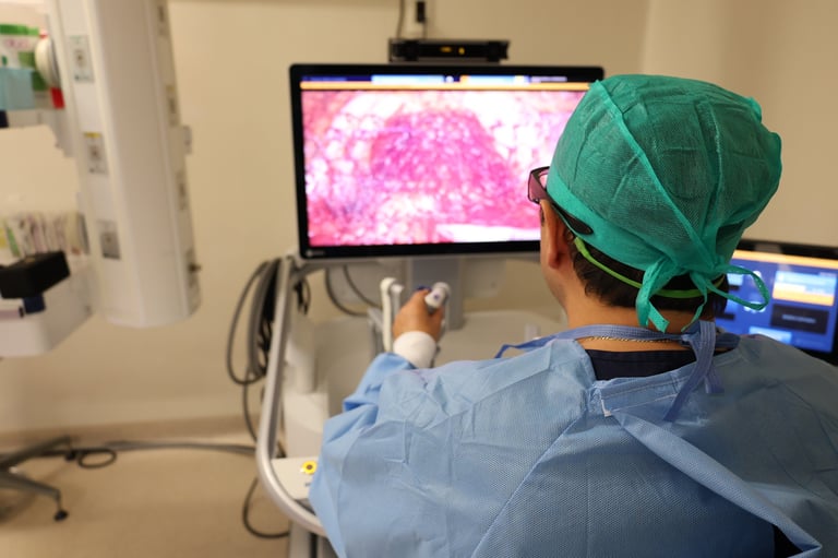 Medical professional in surgical cap viewing microscopy image on monitor during laboratory procedure