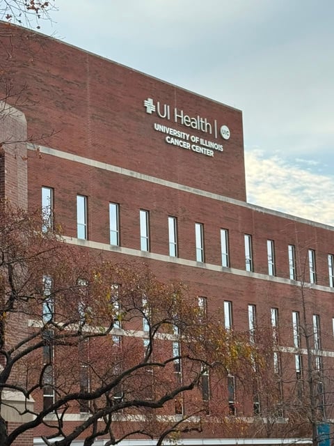 Red brick medical building with white signage reading UI Health University of Illinois Cancer Center