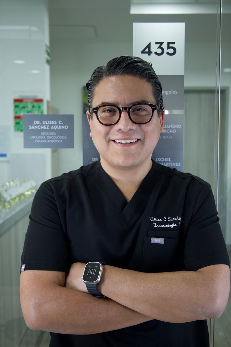 Male healthcare professional smiling at camera wearing glasses and black medical scrubs in an office setting